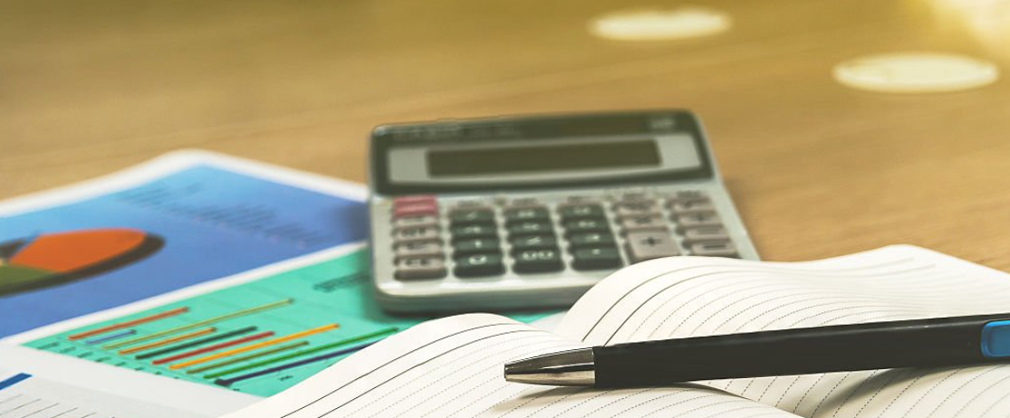 Immagine con penna su un libro aperto e una calcolatrice